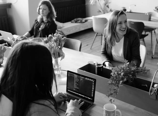 lady sitting infront a mirror laughing while using a laptop